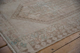 Faded cream, brown, and subtle seafoam geometric patterns on a distressed vintage Oushak rug.