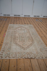 Angled view shows distressed texture and geometric patterns on a vintage Oushak rug.