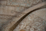Distressed vintage Oushak rug detail, lozenge geometric pattern in muted cream and brown.