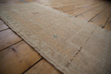 Distressed beige Oushak rug, even pile wear, subtle green motifs, and intact selvage.
