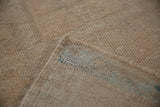 Beige distressed Oushak rug, showing pile texture, original selvage, and blue foundation.