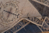 Textured pile and geometric foundation of the distressed Oushak rug, ivory and dark blue.