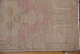 Vintage distressed Oushak rug's low pile, displaying faded beige, dusty pink, and intact selvage.