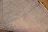 Reverse of Oushak rug, showing hand-knotted beige and dusty pink foundation with vivid mark.