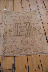 Distressed beige Oushak rug corner showing low pile and bronze geometric patterns.