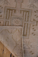 Vintage distressed Oushak rug detail showing hand-knotted reverse, side selvage, and beige pile.