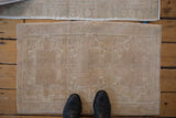 Distressed beige Oushak rug mat featuring faded geometric patterns with even wear.