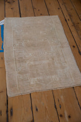 Distressed Oushak rug showcasing even wear across knot heads and faded geometric pattern.