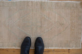 Black shoes on vintage distressed Oushak rug, faded beige and seafoam green medallion.