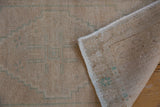 Distressed vintage Oushak rug corner, revealing hand-knotted reverse and intact side cord selvage.