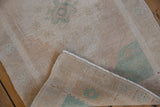 Distressed vintage Oushak rug, showing low pile, hand-knotted reverse, and intact selvage.