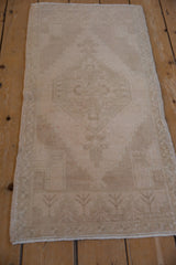Distressed vintage Oushak runner with faded diamond medallion and neutral palette.