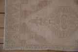 Distressed beige Oushak rug pile, showing even wear and original side selvage.