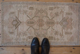 Abrashed field and distressed pile of the vintage Oushak rug's muted floral design.