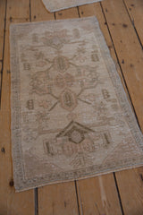 Distressed beige Oushak rug showing low pile texture and intact side selvage.