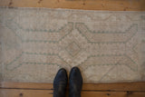 Low, evenly worn hand-knotted pile on a distressed Oushak rug in sand and seafoam green.