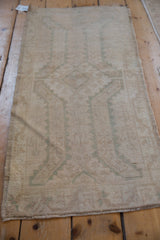 Vintage distressed Oushak mat viewed from an angle, highlighting its time-softened texture and pattern.