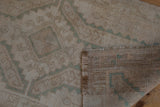 Corner of a vintage Oushak rug folded to show the hand-knotted reverse and low-pile texture.