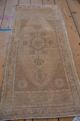Distressed Oushak rug texture with even wear, highlighting faded beige, sand, and pale green patterns.
