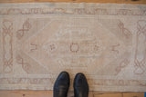 Distressed beige pile and subtle fading motifs on a hand knotted Oushak rug.