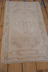 Vintage Distressed Oushak rug corner, showing nuanced scrolling rams horn design motif in muted beige.