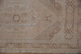 Distressed Oushak rug corner detailing faded scrolling ram's horn motif and fringe.
