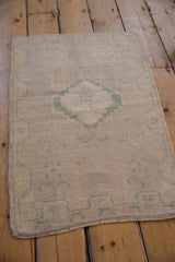 Distressed Oushak rug pile with beige and dusty seafoam green pattern, intact side selvage.