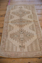 Close-up of distressed Oushak rug, muted beige and sand tones, geometric-floral pattern.