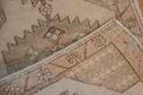 Close-up of distressed vintage Oushak rug's beige pile, woven back, and original selvage.