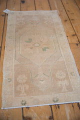 Vintage distressed Oushak mat, beige with faded seafoam green medallion, showing even pile wear.