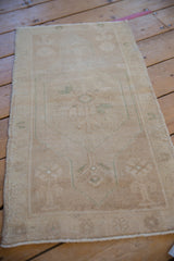 Distressed vintage Oushak rug with worn beige pile and faint seafoam green plant motifs.