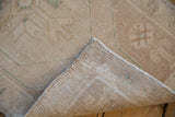 Distressed beige Oushak rug showing hand-knotted reverse foundation and worn pile.