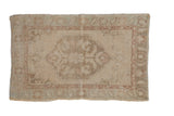 Distressed vintage Oushak rug with a stepped medallion in soft beige, mauve, and pale green.
