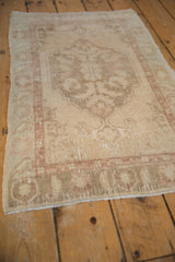 High-angle view of a distressed vintage Oushak rug, showing its even wear and soft sand and mauve colors.