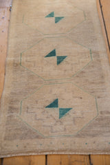 Distressed beige Oushak rug section, pale turquoise geometric medallion with pinwheel motifs.