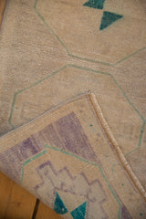 Folded vintage Oushak rug corner revealing time-softened beige pile, geometric patterns, and intact selvage.