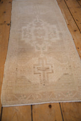 Distressed pile texture with faded stepped medallion and floral motifs on vintage Oushak runner.