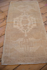 Distressed vintage Oushak runner showing faded beige geometric pattern and intact side selvage.