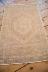Distressed Oushak rug mat showing its textural beige pile and faded hexagonal hook latch motif.