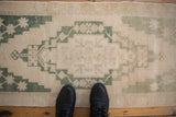 Distressed vintage Oushak rug runner, stepped geometric medallion with green floral motifs.