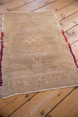 Angled view highlighting the even wear and distressed texture of a vintage beige Oushak rug.