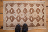 Distressed Oushak rug mat with even wear, serrated floral guls in dusty copper brown and ivory.