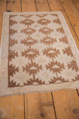 Distressed texture of vintage Oushak rug, with serrated brown geometric patterns on ivory.