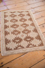 Close-up of distressed Oushak rug shows dusty copper serrated guls, wear, and side selvage.