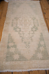 Angled view of a vintage Oushak runner, showing its distressed texture and pale green medallion.