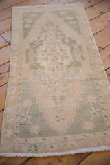 Soft, low pile of a distressed Oushak runner in muted seafoam green and sand tones.