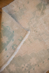 Corner of a vintage Oushak rug showing its hand-knotted foundation and intact side selvage.