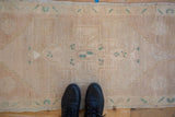 Distressed Oushak rug's faded beige pile, dusty rose abrash, and turquoise green motifs.