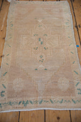 Distressed Oushak rug corner showing dusty turquoise green motifs, wear, and side selvage.