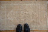 Vintage distressed Oushak rug mat with subtle faded pattern and soft beige tones.